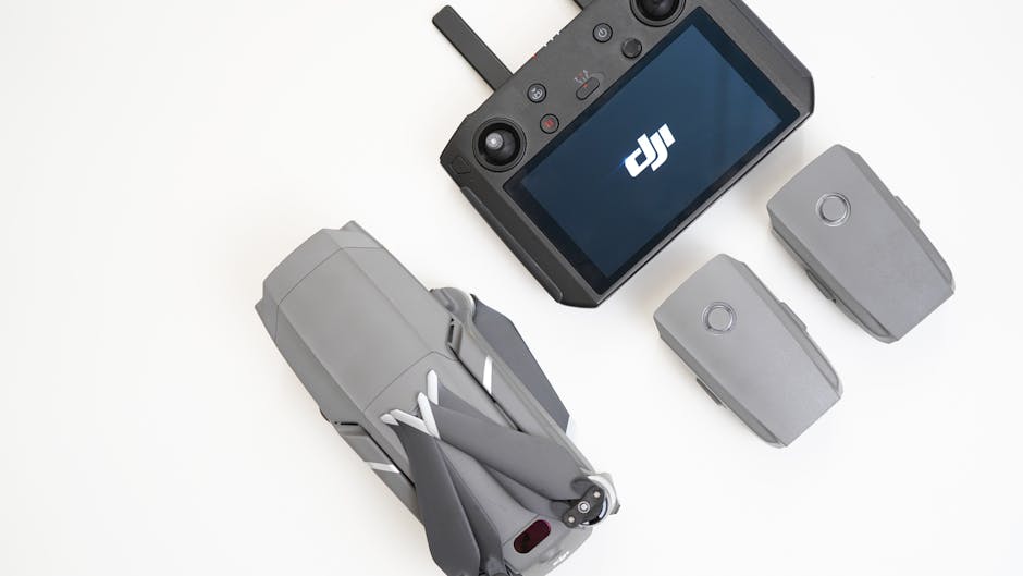 Close de um drone DJI, controlador e baterias em uma superfície branca para fotografia aérea.