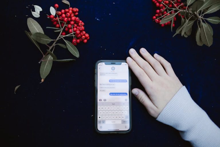 Uma mão ao lado de um smartphone mostrando uma conversa por mensagem de texto, cercada por bagas vermelhas.